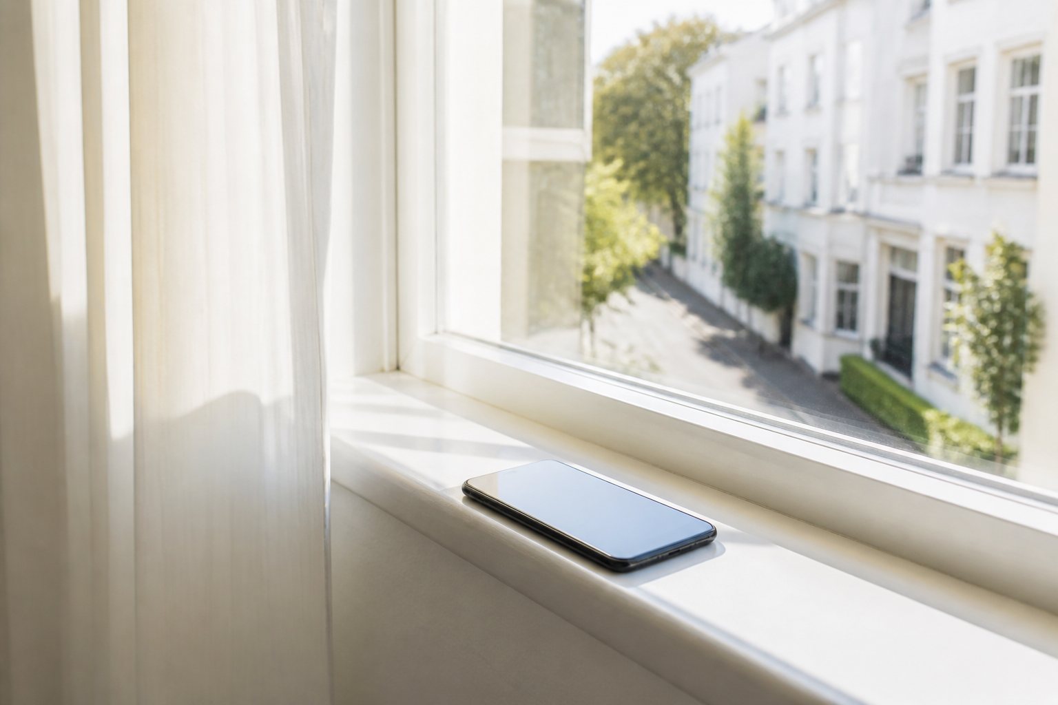 Phone on a bright windowsill looking onto a sunlit street